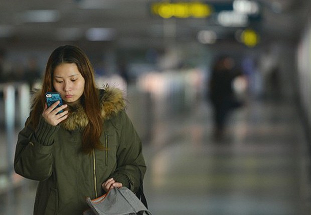 Jovem chinesa usando o seu mobile onde tem acesso à Bíblia Jovem chinesa usando o seu mobile onde tem acesso à Bíblia