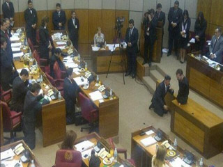 Nick Vujicic, sobre o móvel, na parte da frente do Congresso, conduz deputados do Paraguai em oração - de joelhos